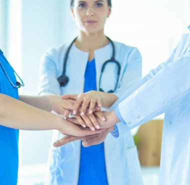 Bir grup doktor ellerini birleştiriyor. Yakın plan.
