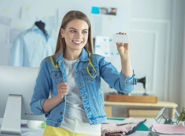 Mooie jonge vrouw ontwerper met visitekaartje in het kantoor — Stockfoto