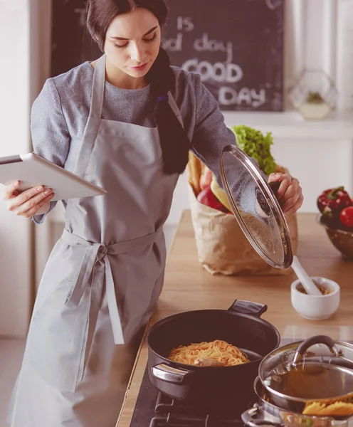 Žena pečení doma po recept na tabletu — Stock fotografie