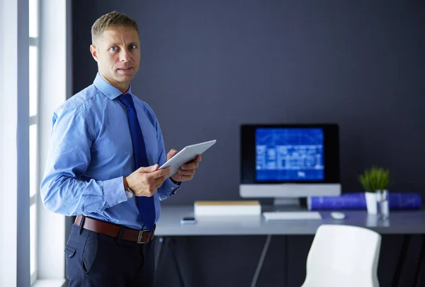 Homme d'affaires souriant avec pavé tactile debout sur le lieu de travail au bureau — Photo