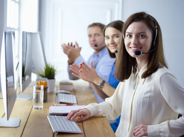 Ritratto di giovane operatore di call center che indossa auricolari con colleghi che lavorano in background in ufficio — Foto Stock