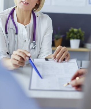 Doktor ve hasta tıbbi kayıtları olan bir dosyayı inceliyor. Tekerlekli sandalyede oturuyor.