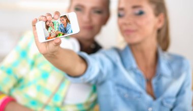 Kadınlar selfie çekiyor. İki çekici genç kadın selfie çekiyor ve gülümsüyor.