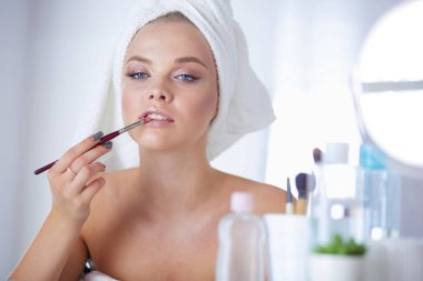 Genç bir kadının banyoya yüz pudrası sürerken fotoğrafı.