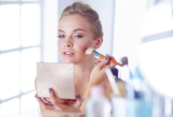 A picture of a young woman applying face powder in the bathroom — Stock Photo, Image