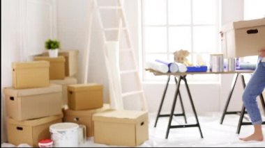 Genç dişi yeni bir dairede onarım yapıyor. Güzel kız, dairede duvar boyuyor.