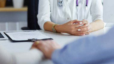 Konsantrasyonu olan hastayı dinleyen doktor, ofiste masa başında oturuyor.