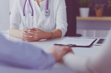 Konsantrasyonu olan hastayı dinleyen doktor, ofiste masa başında oturuyor.