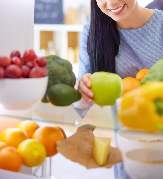 Mosolygó nő vesz egy friss gyümölcsöt ki a hűtőből, egészséges étel koncepció — Stock Fotó