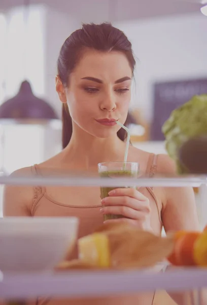 Ung kvinna med glas välsmakande hälsosam smoothie vid bordet i köket — Stockfoto