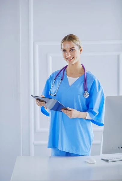 Médecin souriante avec un dossier en uniforme debout — Photo
