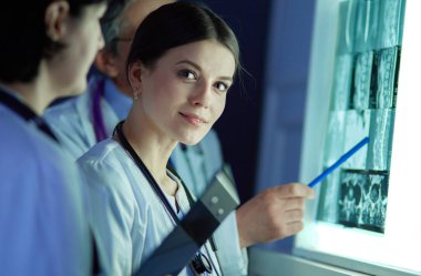 Bir grup doktor bir klinikte röntgenleri inceliyor, teşhis koymayı düşünüyorlar.
