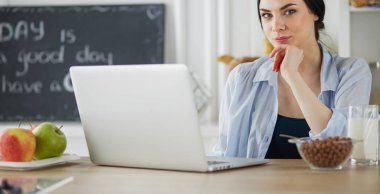 bir fincan kahve ve bir dizüstü bilgisayar mutfakta bir kadınla