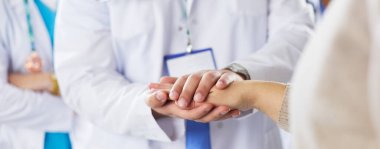 Doktorlar ve hemşireler tıbbi bir ekipte el ele tutuşuyorlar.