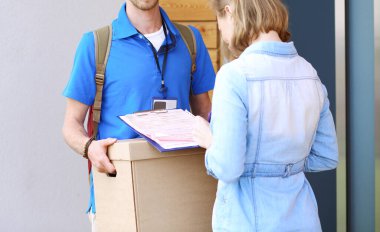 Mavi üniformalı gülümseyen kurye servis konseptine paket kutusu teslim eden teslimatçı. Mavi üniformalı gülümseyen teslimatçı.