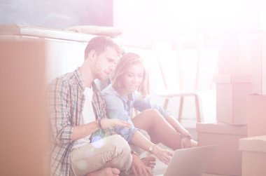 Genç bir çift yeni ev içinde hareket. Oturma ve açma sonra rahatlatıcı. Bir şey üstünde laptop arıyorum. Genç Çift