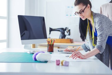 Güzel moda tasarımcısı stüdyoda duruyor.
