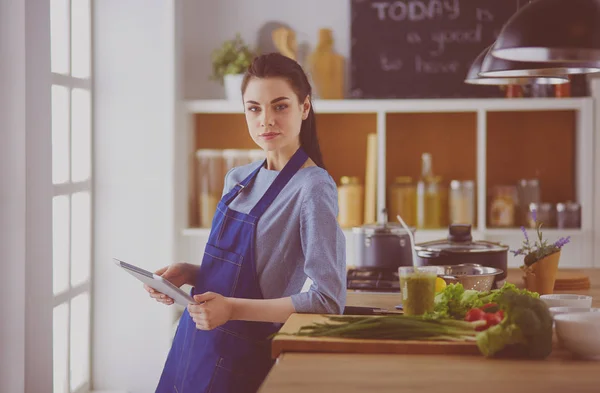 Junge Frau kocht mit Tablet-Computer in ihrer Küche — Stockfoto