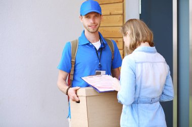 Mavi üniformalı gülümseyen kurye servis konseptine paket kutusu teslim eden teslimatçı. Mavi üniformalı gülümseyen teslimatçı.