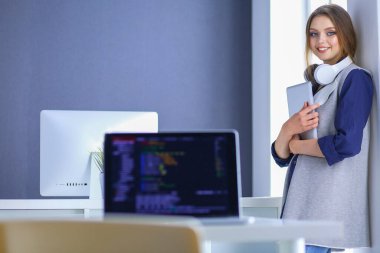 Ofisteki masanın önünde duran genç iş kadını.