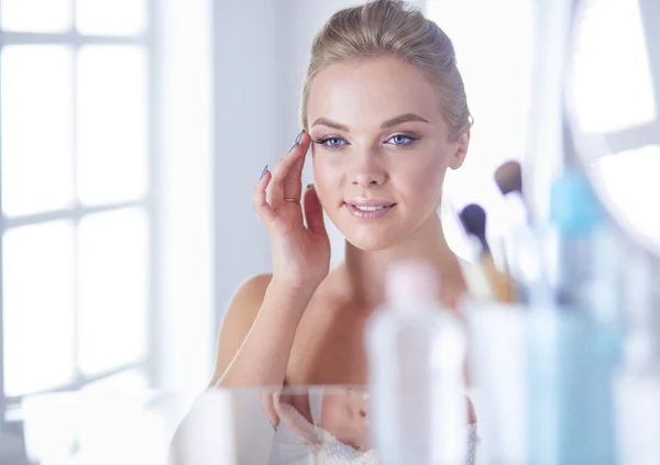 Jonge vrouw in badjas op zoek in badkamer spiegel — Stockfoto