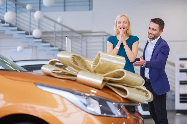 Een man maakt een geschenk - een auto aan zijn vrouw. Ze is hier verbaasd over. Ze zijn erg blij over — Stockfoto