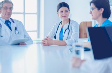 Ciddi bir tıbbi ekip hastaları parlak bir ofiste tartışıyor.