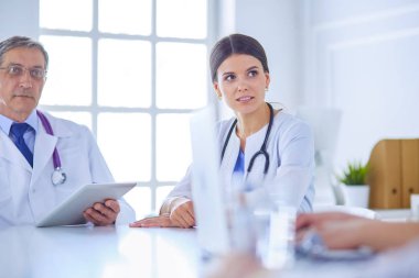 Doktorlar hastane konferans odasında birbirlerine danışıyorlar.