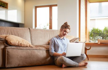 oturma odasında yere üstünde laptop ile mutlu bir kadın