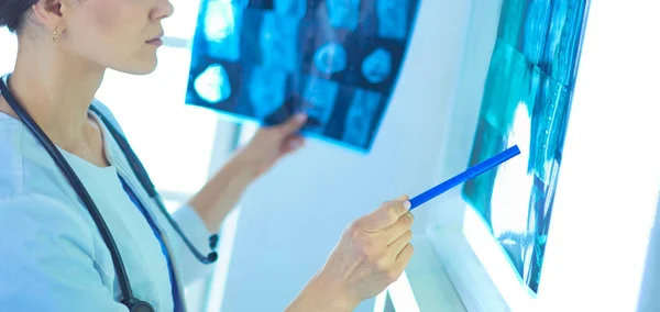 Joven doctora sonriente con estetoscopio apuntando a rayos X en el consultorio médico —  Fotos de Stock