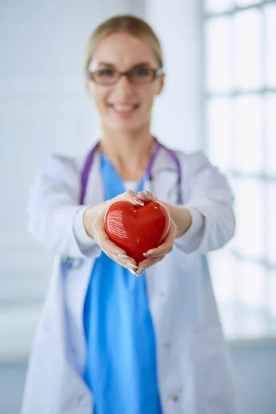 Médica com estetoscópio a segurar o coração nos braços. Conceito de saúde e cardiologia em medicina — Fotografia de Stock