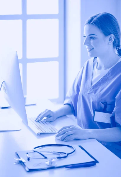 Young tired exhausted woman sitting at desk, working on computer with medical documents