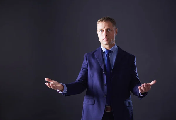 Portrait of successful cheerful cute young man presenting new product, showing copy spase on her palm on grey background — Stock Photo, Image