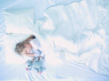 çocuk oyuncak oyuncak ayı ile yatakta uyur küçük kız.