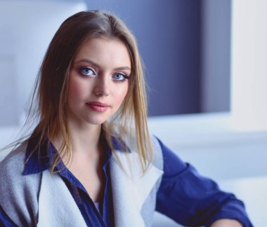 Ofis masasında çalışan ve dizüstü bilgisayarla yazan kendine güvenen genç bir iş kadını.