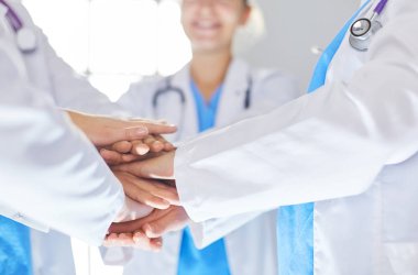 Doktorlar ve hemşireler tıbbi bir ekipte el ele tutuşuyorlar.