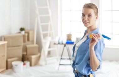 Güzel gülümseyen kadın evin iç duvarını boya ile boyuyor.