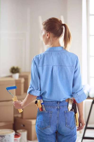 Ganska smilling kvinna målning interiör vägg i hemmet med färg roller — Stockfoto