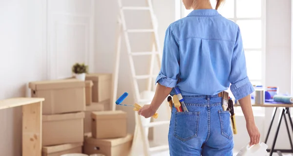 Bella donna sorridente pittura parete interna della casa con rullo di vernice — Foto Stock