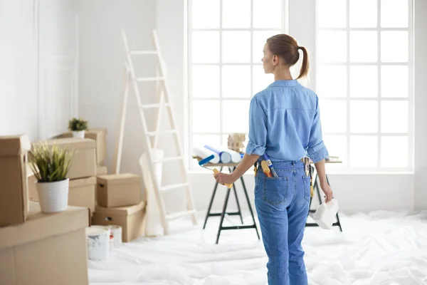 Donna felice dipinge parete con rullo a casa — Foto Stock