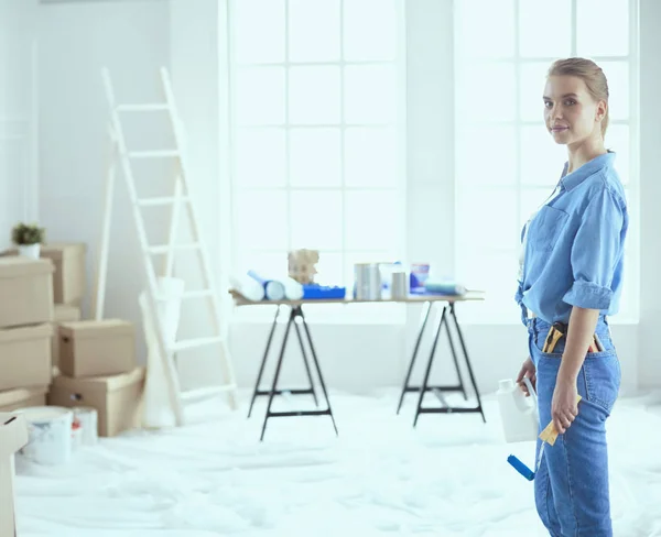 Ganska smilling kvinna målning interiör vägg i hemmet med färg roller — Stockfoto