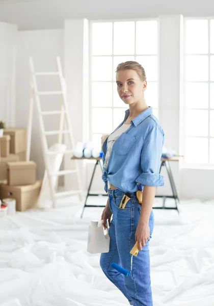 Ganska smilling kvinna målning interiör vägg i hemmet med färg roller — Stockfoto