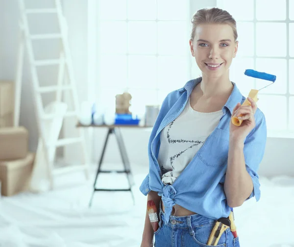 Bella donna sorridente pittura parete interna della casa con rullo di vernice — Foto Stock