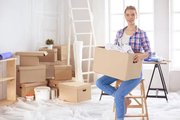 Een mooie alleenstaande jonge vrouw uitpakken dozen en verhuizen naar een nieuw huis — Stockfoto