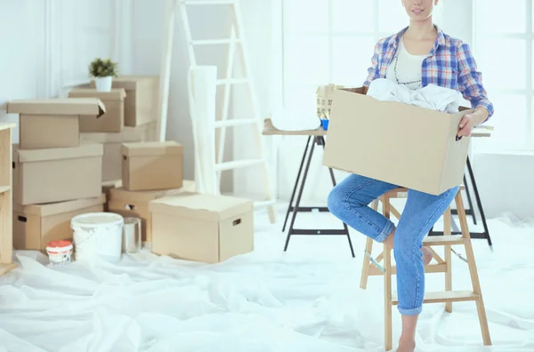 Μια όμορφη ανύπαντρη γυναίκα ξεπακετάρει κουτιά και μετακομίζει σε νέο σπίτι. — Φωτογραφία Αρχείου