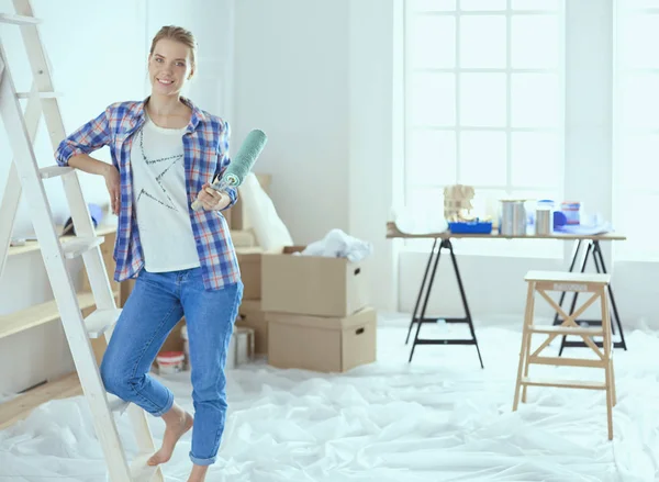 Sonriendo hermosa mujer pintando la pared interior del hogar — Foto de Stock