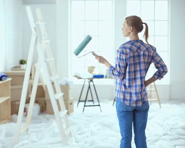 Beautiful young woman doing wall painting, standing near ladder — Stock Photo, Image