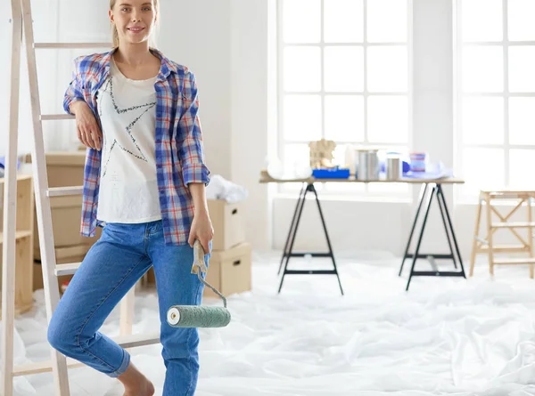 Smiling beautiful woman painting interior wall of home