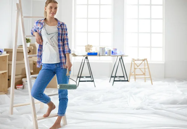 Sonriendo hermosa mujer pintando la pared interior del hogar — Foto de Stock