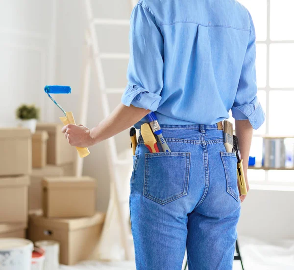 Mujer bonita pintando la pared interior del hogar con rodillo de pintura — Foto de Stock